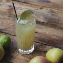 MÃ©nage Ã  trois cocktail with apples and lime on a wooden table
